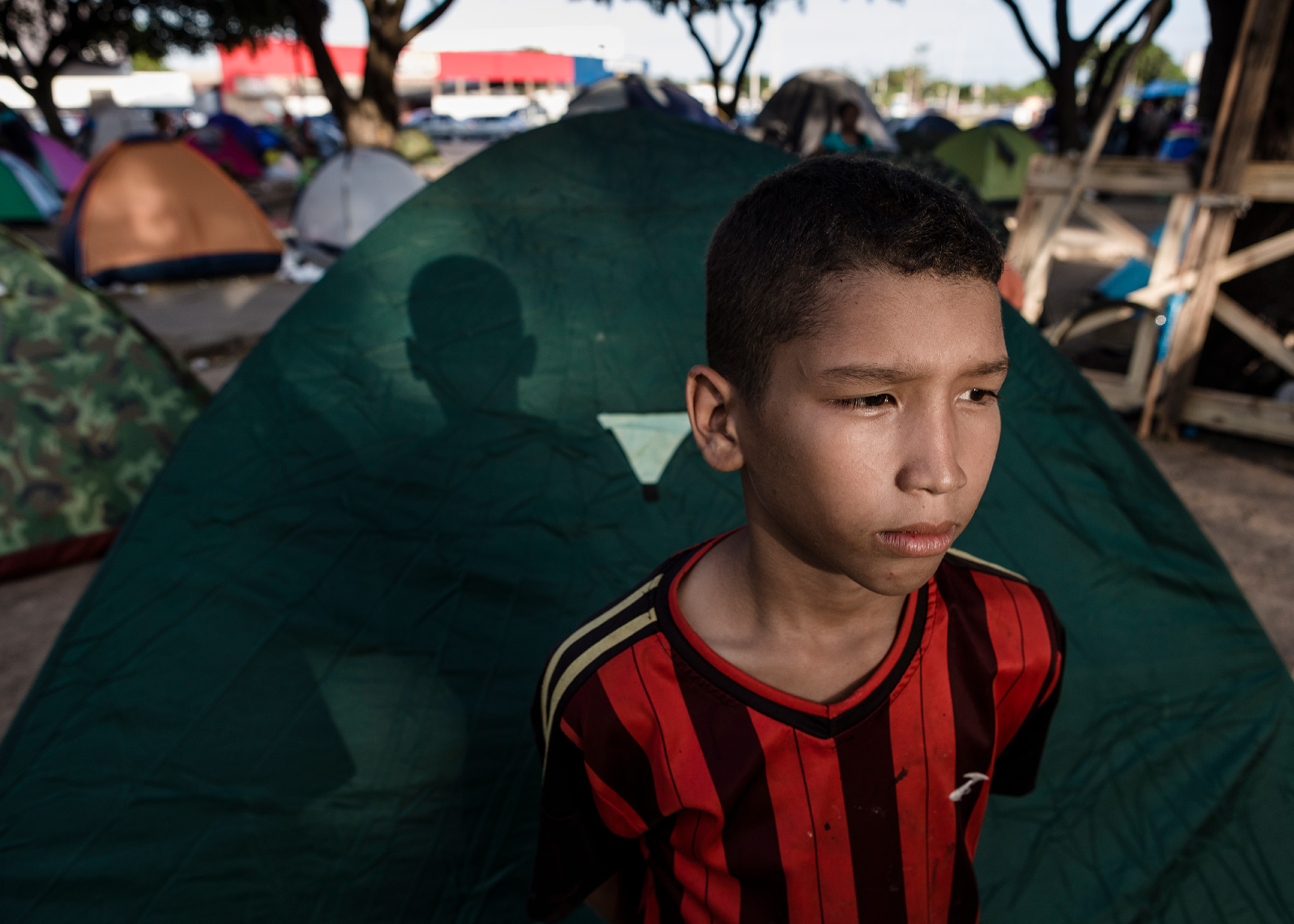 A boy nearby his family's tent in a Boa Vista's street, 2018.